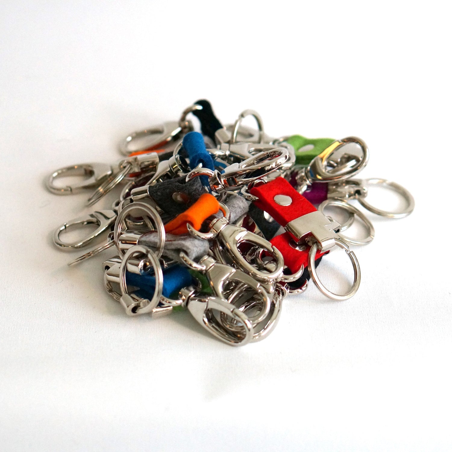 stapel met verschillende kleuren wol vilten sleutelclips, rood, groen, oranje, blauw, antraciet, violet.
A stack of different colours of wool felt key clips: red, green, orange, blue, anthracite, and violet. studio ROWOLD