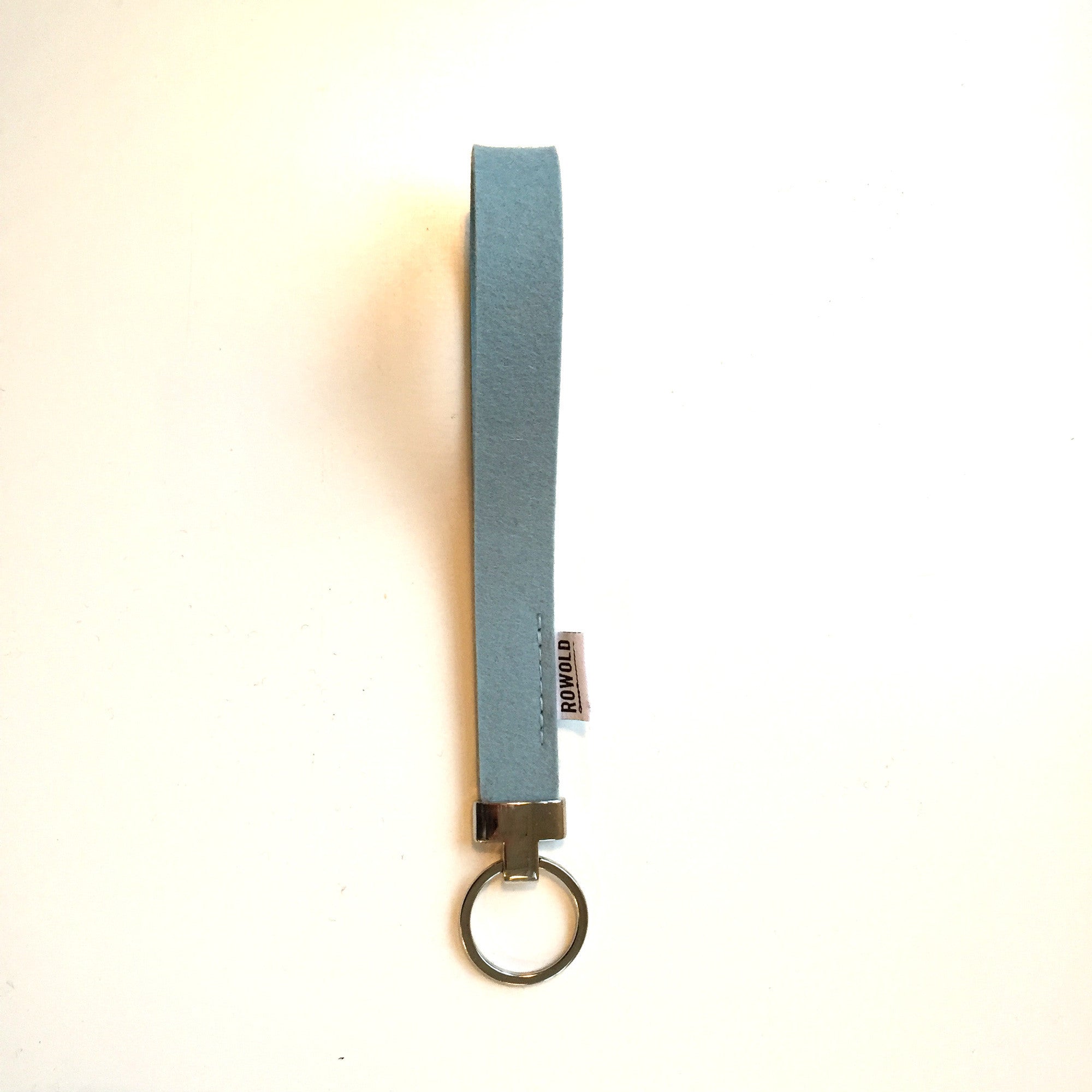 Gemêleerde pols sleutelhanger in wit merinowol vilt met subtiele nuances, handgemaakt in Nederland met een elegant nikkel eindstuk.